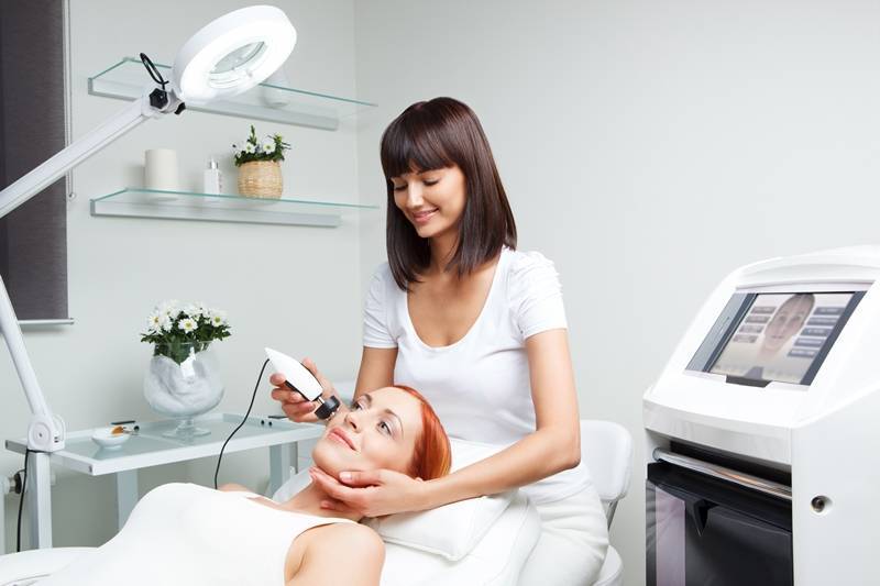 A therapist performing facial laser hair removal to a client