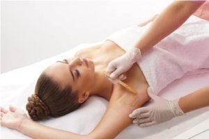 A women laying down having her underarms waxed